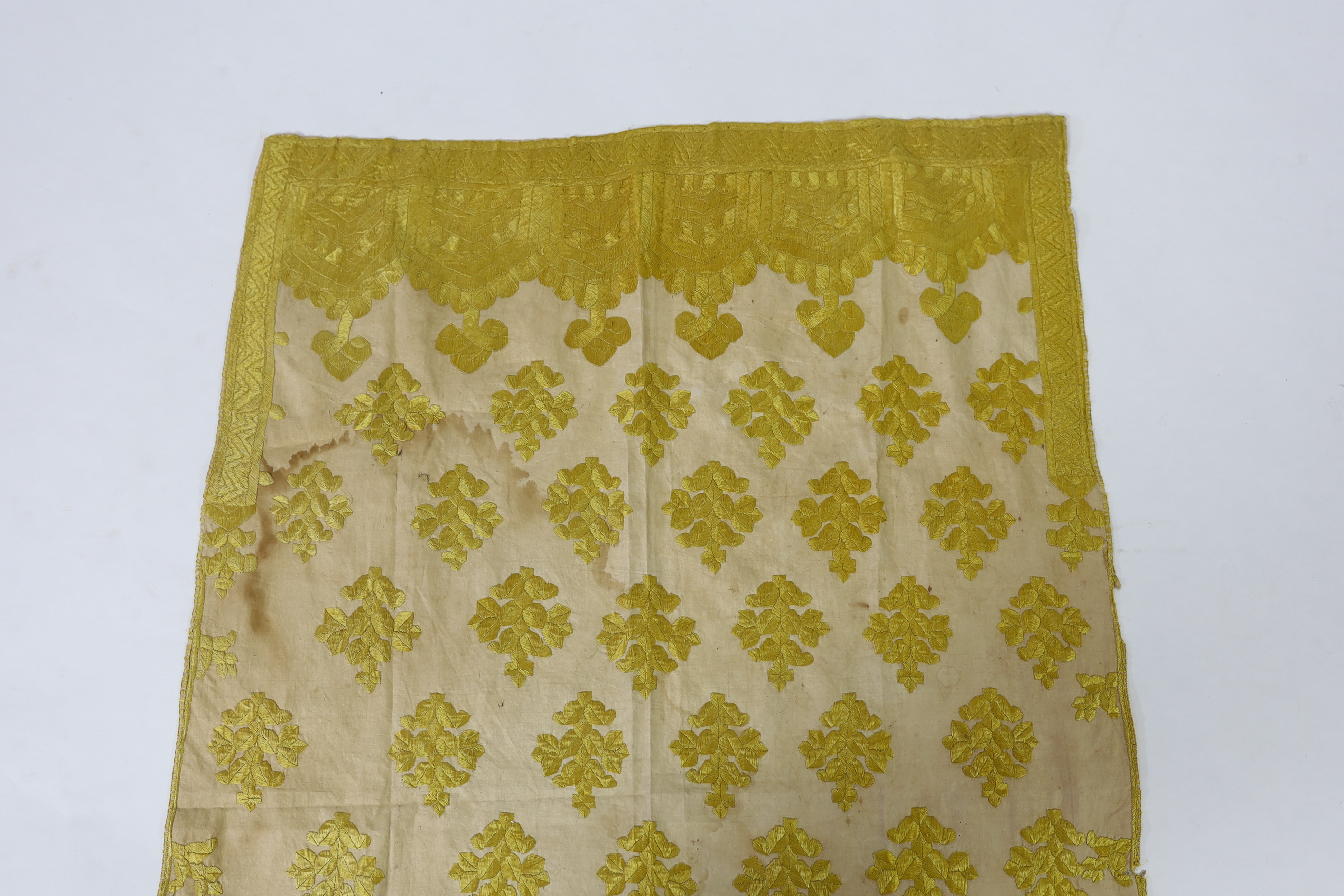 An early 20th century North Indian cotton yellow silk hand embroidered panel, with wide embroidered borders and all over stylistic spot motifs, 122 cm long x 80cm wide